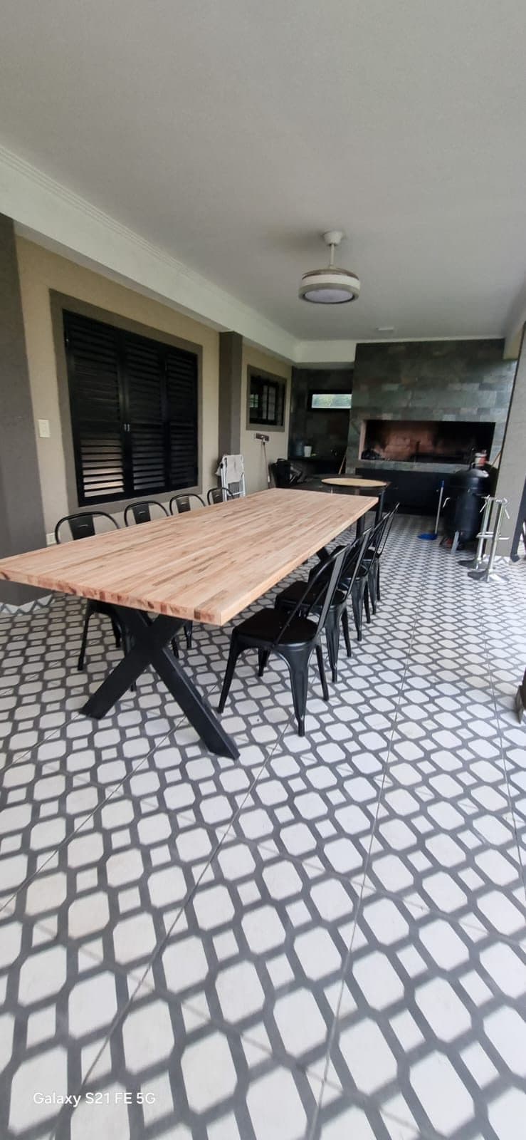 Mesa larga de madera con sillas para comer en grupo bajo el quincho